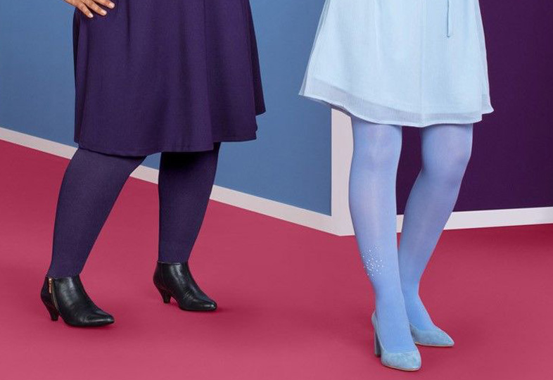 Beine von zwei Frauen mit Strumpfhosen, eine trägt dunkelblaue Strumpfhose und schwarze Schuhe, die andere hellblaue Strumpfhose mit hellen Schuhen